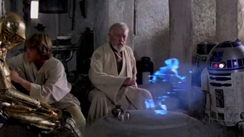 C-3PO, Obi-wan, and R2-D2 in hut with hologram